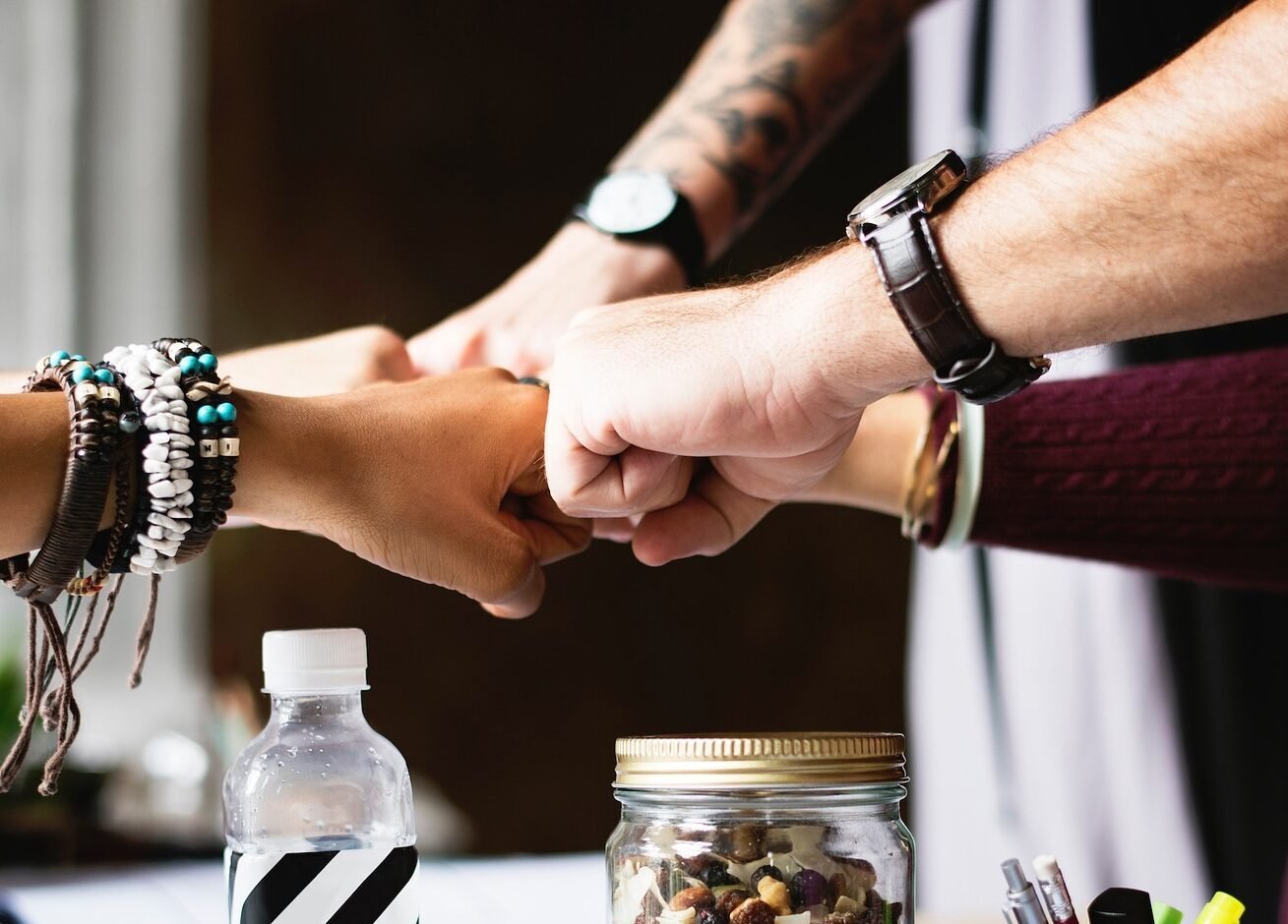 Varias personas chocando los puños, en un entorno de oficina moderna, en señal de equipo