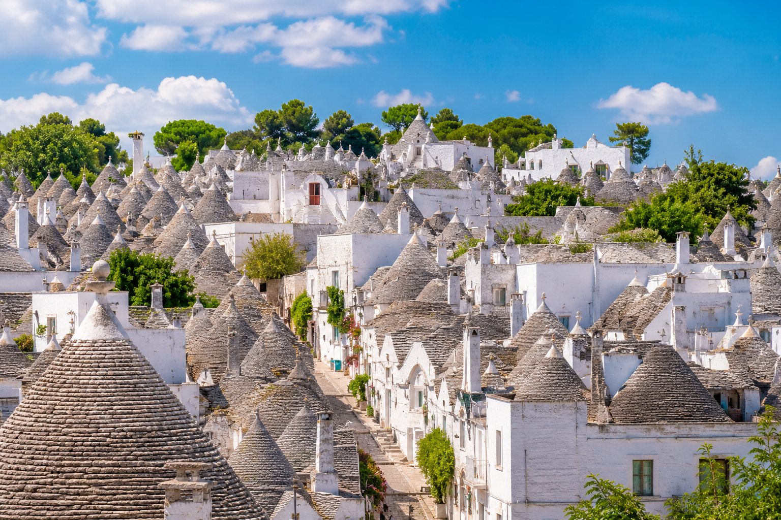 panorámica del barrio Rione Monti en Alberobello, con los tejados cónicos ascendiendo por la colina y la piedra blanca contrastando con el cielo azul (IA)
